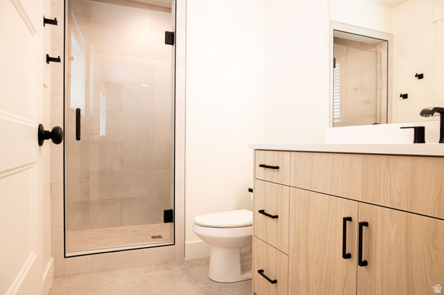2218 South 635 West, Unit A Perry, UT 84302 - Photo 7 of 18 Glass-enclosed shower with black trim, light wood-finish vanity with black hardware, white countertop, and tiled flooring