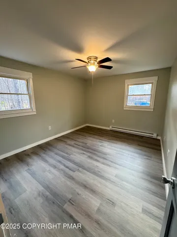 an empty room with wooden floor chandelier fan and windows