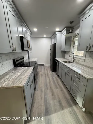 a large kitchen with a sink a counter top space stainless steel appliances and cabinets