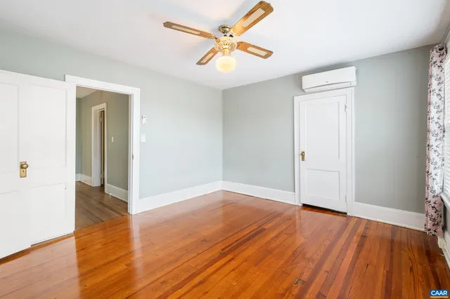 a view of empty room with wooden floor and fan