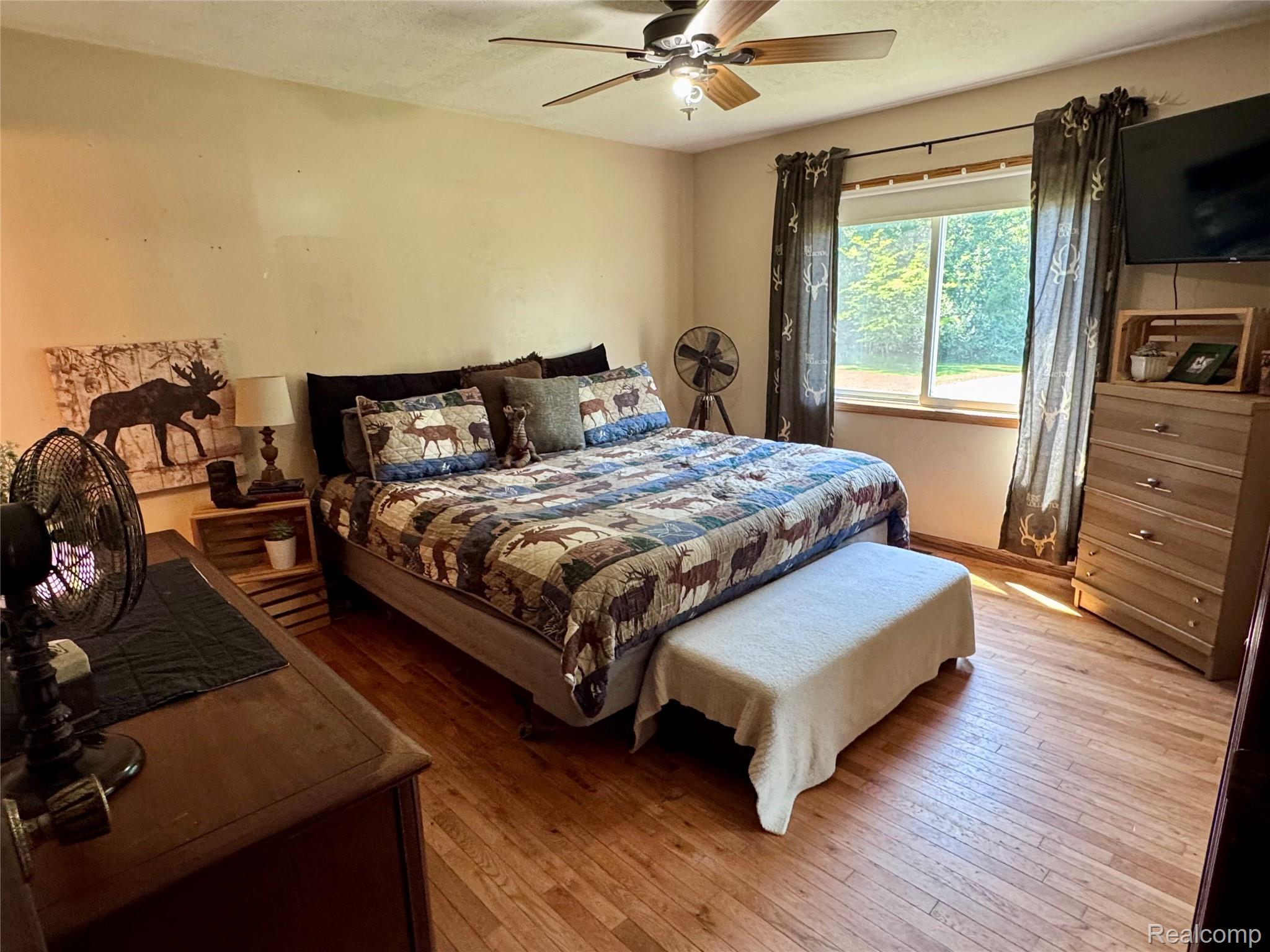 2850 Tin Bill Road Caro, MI 48723 - Photo 6 of 10 Bedroom featuring wood-finish flooring, a ceiling fan with integrated lighting, and a large window
