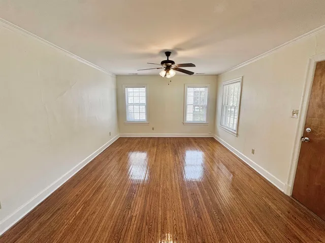 an empty room with wooden floor and windows