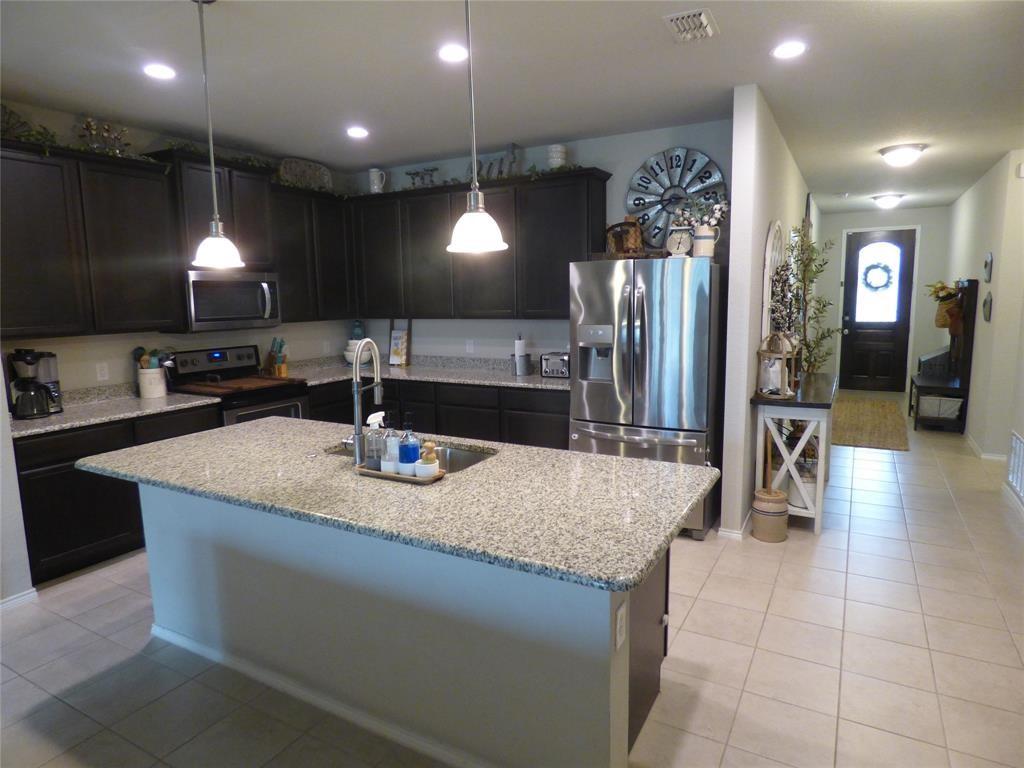 7416 Boat Wind Road Fort Worth, TX 76179 - Photo 12 of 18 a kitchen with kitchen island a sink and a refrigerator