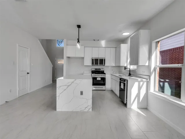 a kitchen with granite countertop a sink stainless steel appliances and cabinets