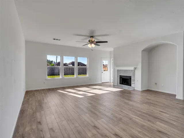 a view of an empty room with a fireplace and wooden floor