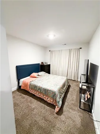 a bedroom with a bed flat screen tv and window