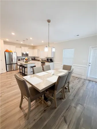 a dining room with stainless steel appliances wooden floors a table and chairs