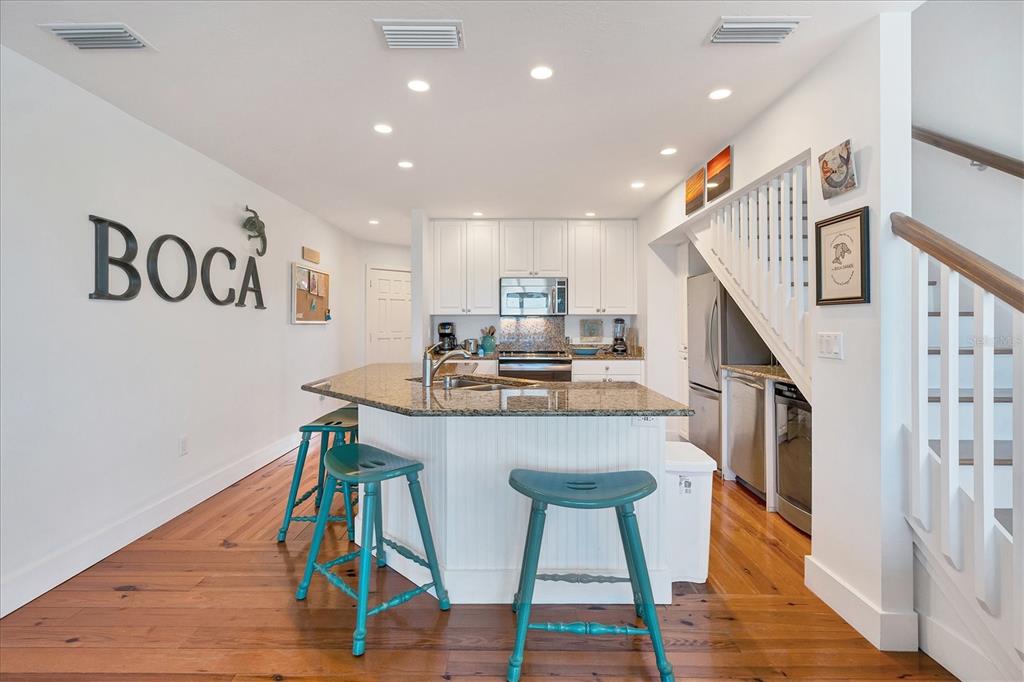 480 Gulf Boulevard, Unit 6 Boca Grande, FL 33921 - Photo 18 of 49 a kitchen with stainless steel appliances granite countertop a kitchen island a hardwood floor and chairs