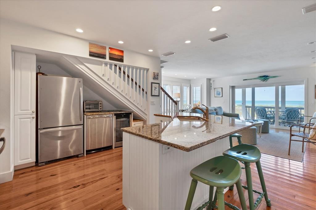 480 Gulf Boulevard, Unit 6 Boca Grande, FL 33921 - Photo 20 of 49 a kitchen with stainless steel appliances kitchen island granite countertop a refrigerator a stove a dining table and chairs with wooden floor
