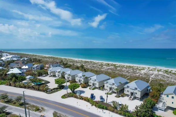 an aerial view of ocean and residential houses with outdoor space