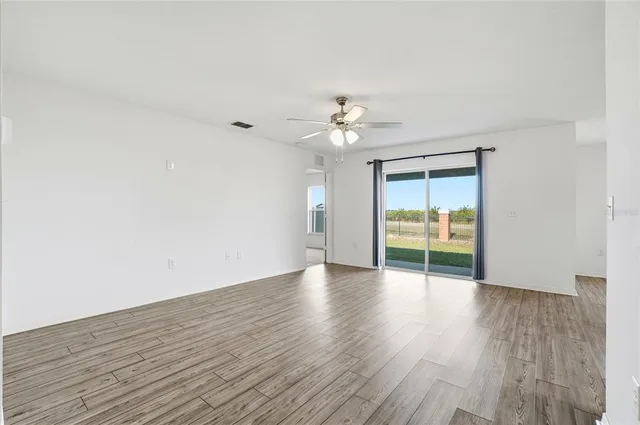 a view of an empty room with a window and wooden floor