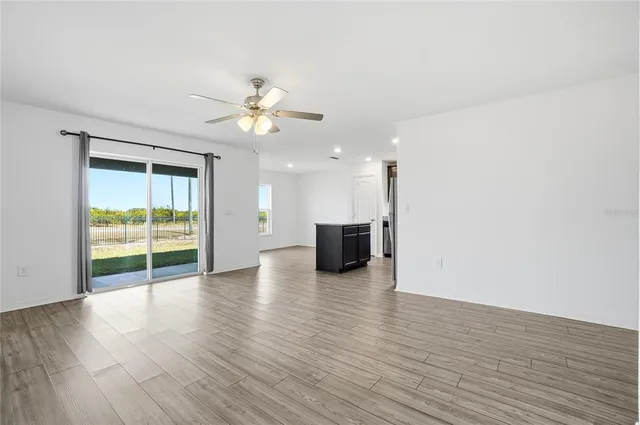 a view of an empty room with a window and wooden floor
