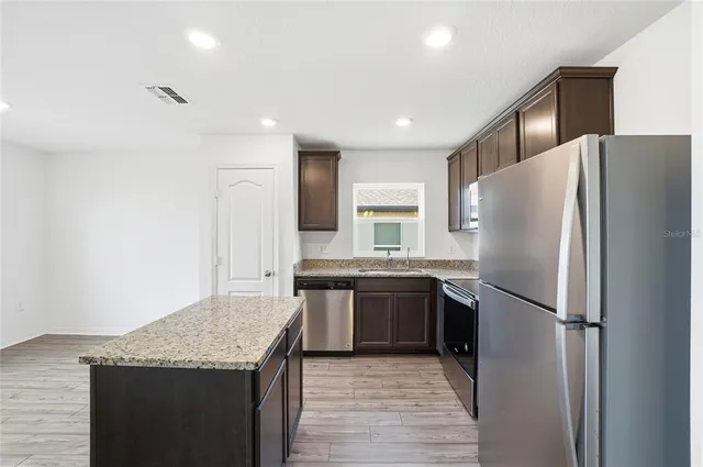 a kitchen with stainless steel appliances granite countertop a refrigerator and a sink