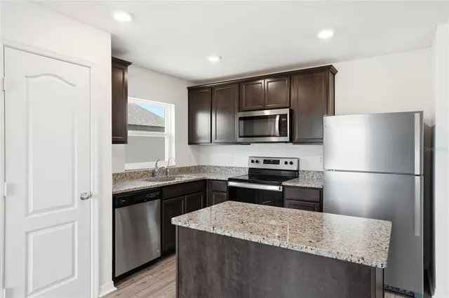 a kitchen with granite countertop a refrigerator stove and sink