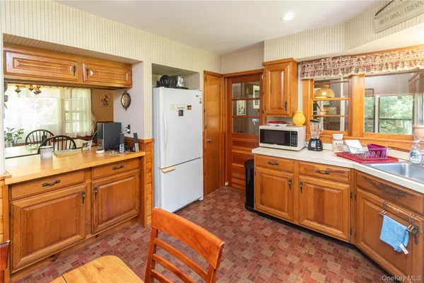 a large kitchen with kitchen island a large window a sink stainless steel appliances and cabinets