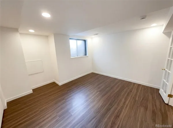 an empty room with wooden floor and windows