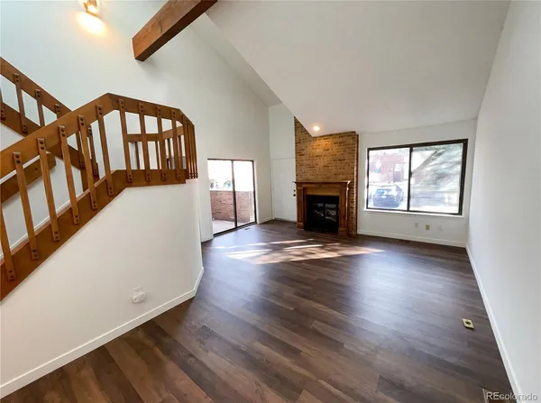 an empty room with wooden floor fireplace and windows