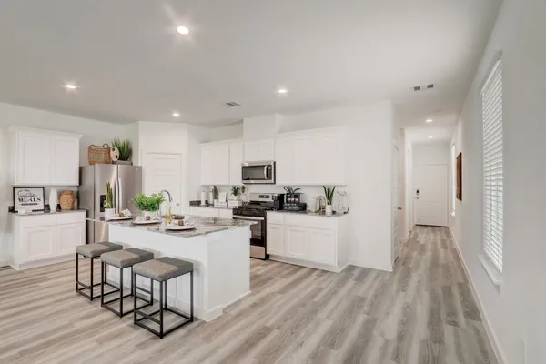 a large white kitchen with lots of counter space and stainless steel appliances