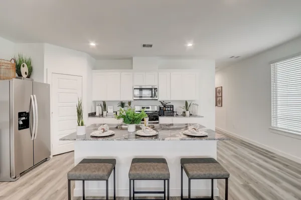 a kitchen with stainless steel appliances granite countertop a dining table chairs and chandelier