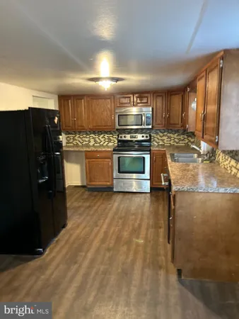 a kitchen with stainless steel appliances kitchen island granite countertop a refrigerator a stove a sink and dishwasher