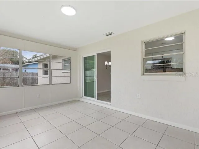 an empty room with kitchen view and wooden floor