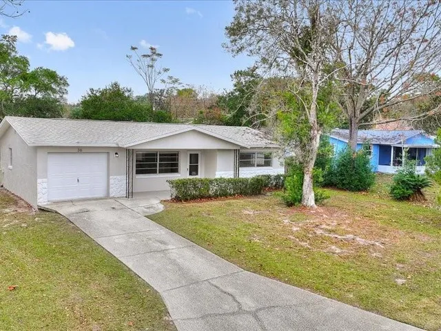 a front view of a house with a garden and trees