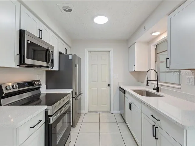 a kitchen with stainless steel appliances granite countertop a sink stove and microwave