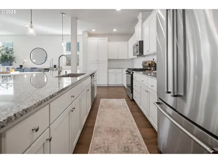 a large kitchen with stainless steel appliances granite countertop a stove a sink dishwasher and a microwave oven with white cabinets