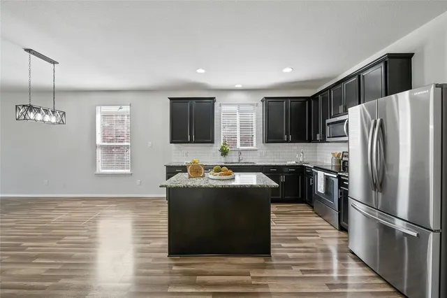 a kitchen with granite countertop a refrigerator and a stove top oven