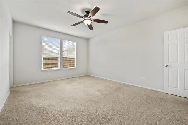 an empty room with ceiling fan and windows
