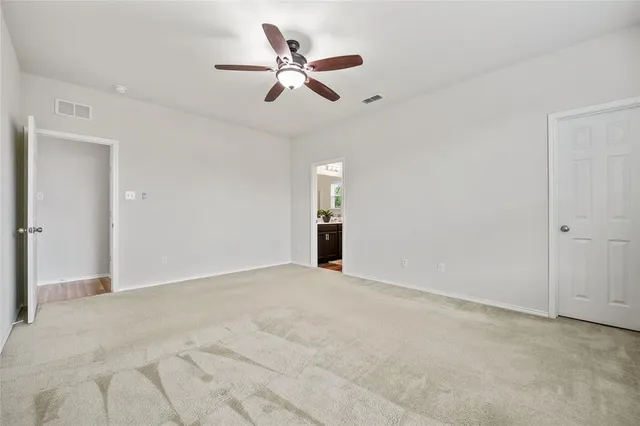 an empty room with ceiling fan and window