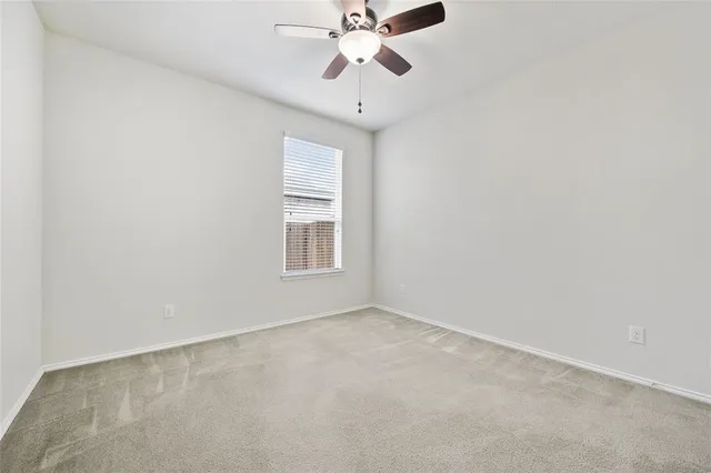 an empty room with windows and ceiling fan