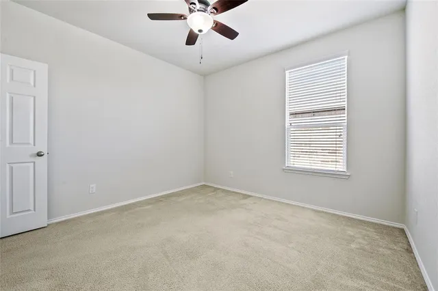 an empty room with a window and a fan