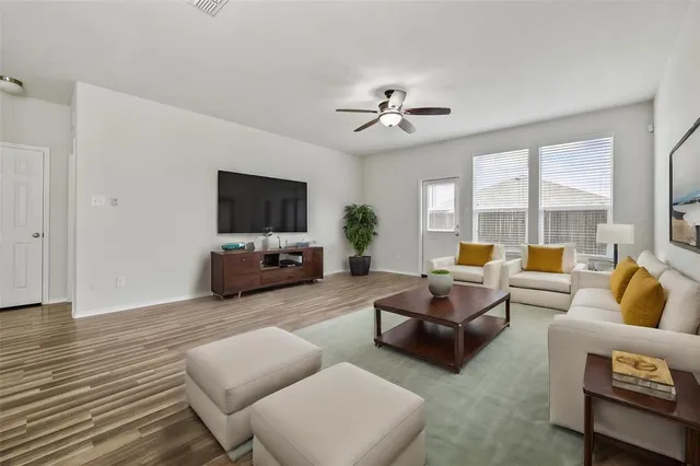 a living room with furniture flat screen tv and a large window