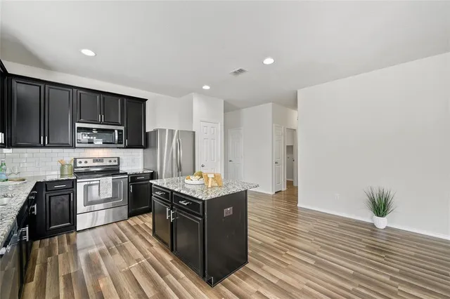 a kitchen with stainless steel appliances granite countertop a stove cabinets and wooden floor