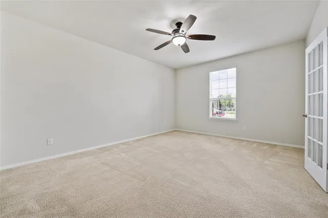 an empty room with windows and fan