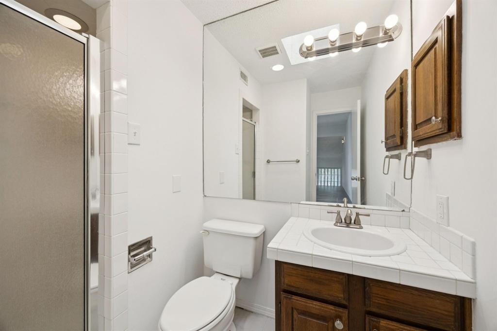 18240 Midway Road, Unit 904 Dallas, TX 75287 - Photo 21 of 26 a bathroom with a toilet a sink and mirror