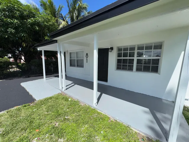 a view of a yard in front of a house with a large tree