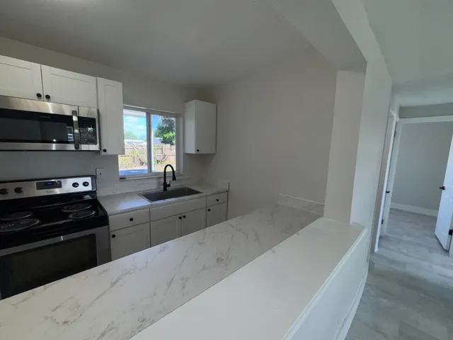 a kitchen with granite countertop a stove a sink and a granite counter tops