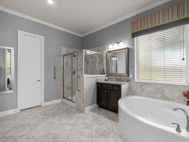 a bathroom with a bathtub a double vanity sink and window