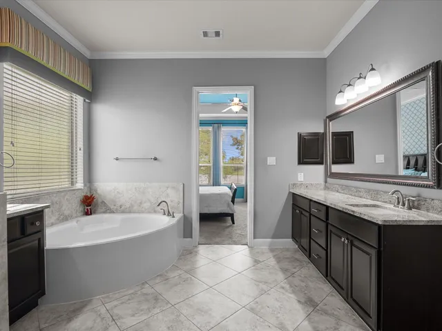 a spacious bathroom with a tub double sink and mirror