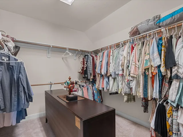 a view of walk in closet with clothes and shoes