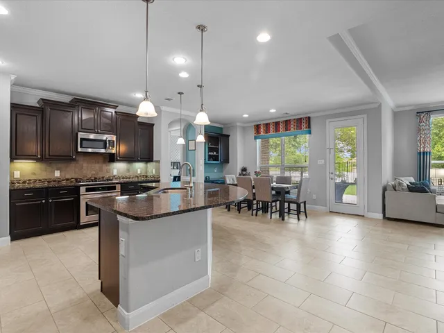 a kitchen with stainless steel appliances kitchen island granite countertop a stove a sink a dining table and chairs with wooden floor