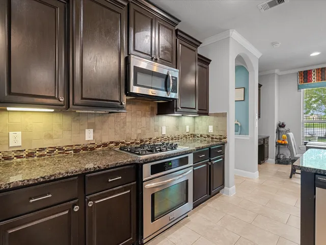 a kitchen with stainless steel appliances granite countertop a stove microwave and refrigerator