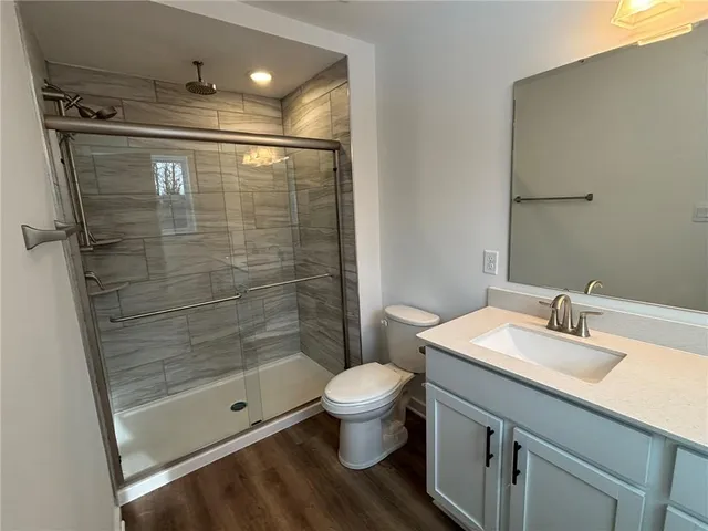 a bathroom with a toilet a sink a mirror and a shower