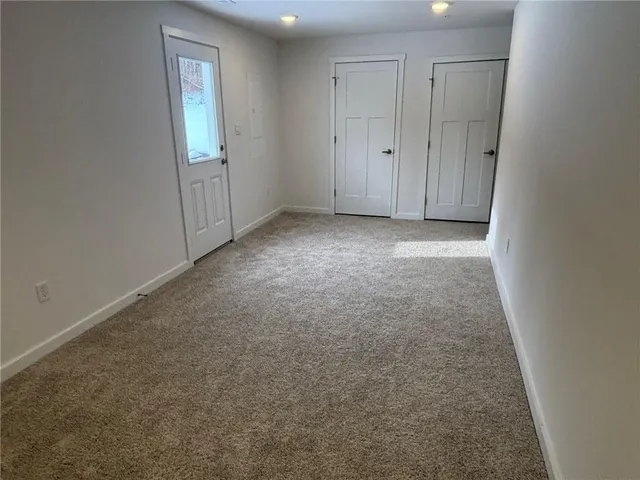 a view of an empty room with closet and a window