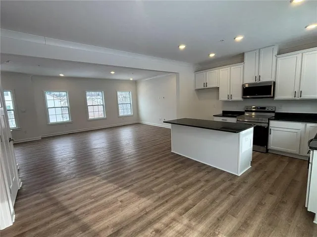 a kitchen with stainless steel appliances wooden floor and large window