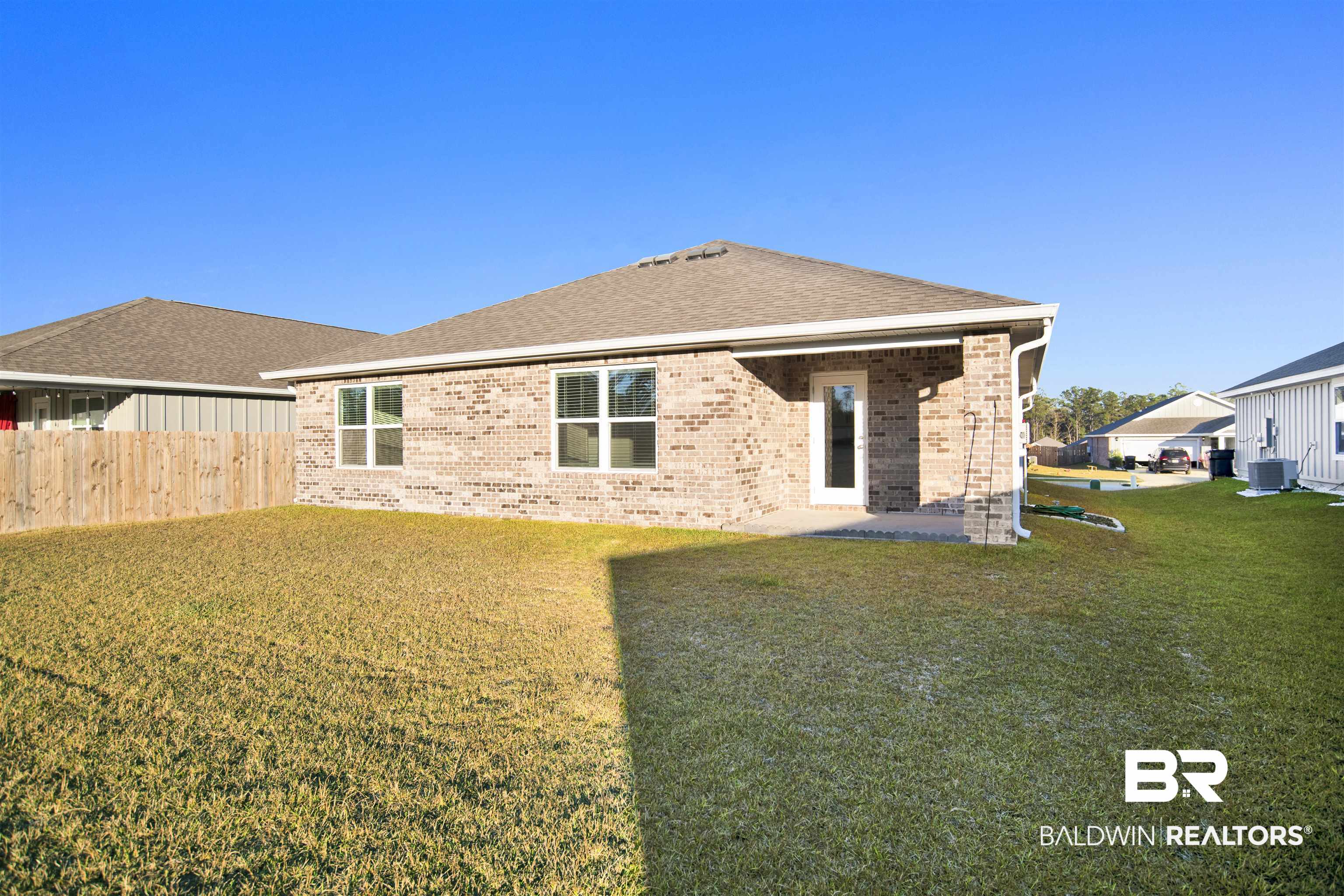 32038 Lyon Road Daphne, AL 36527 - Photo 6 of 30 Back of property with brick siding, a shingled roof, a patio, and a yard