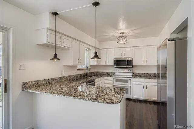 a kitchen with stainless steel appliances granite countertop a sink a stove and a refrigerator