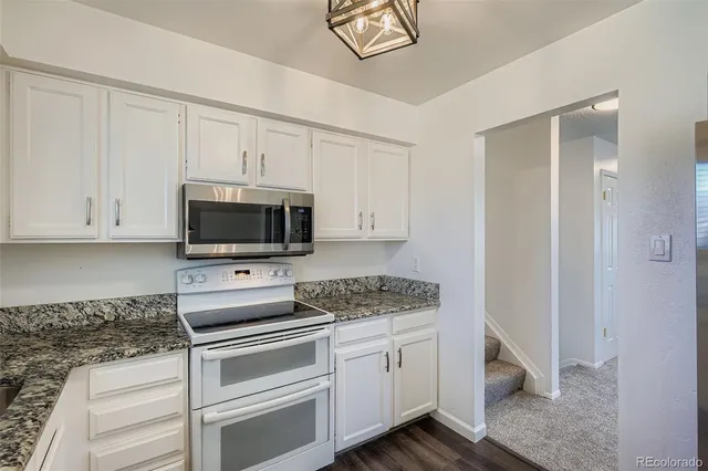 a kitchen with white cabinets and appliances